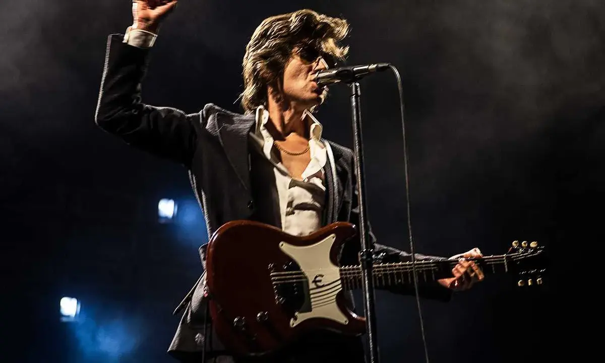Alex Turner från Arctic Monkeys, med knuten näve i luften, spelar gitarr på scen i Stockholm.