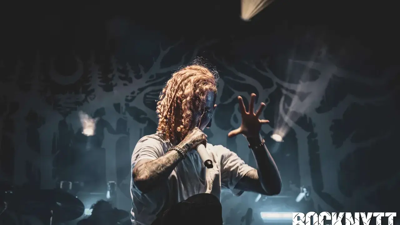 Lorna Shore Sverige: Sångaren med flammigt hår och tatueringar greppar mikrofonen på scenen, omgiven av rök och dramatiskt ljus.