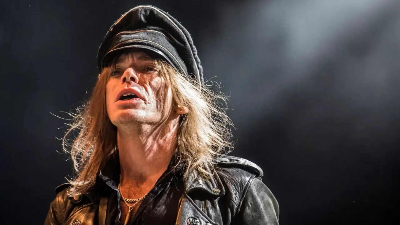Nicke Andersson från Hellacopters, med sin karaktäristiska keps och läderjacka, fångad i ett intensivt ögonblick på scenen.