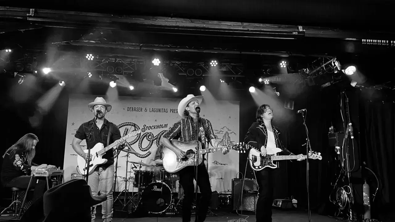 Band spelar på scen i Stockholm, med cowboyhattar och gitarrer. Kanske en hyllning till Fleetwood Mac Stockholm?