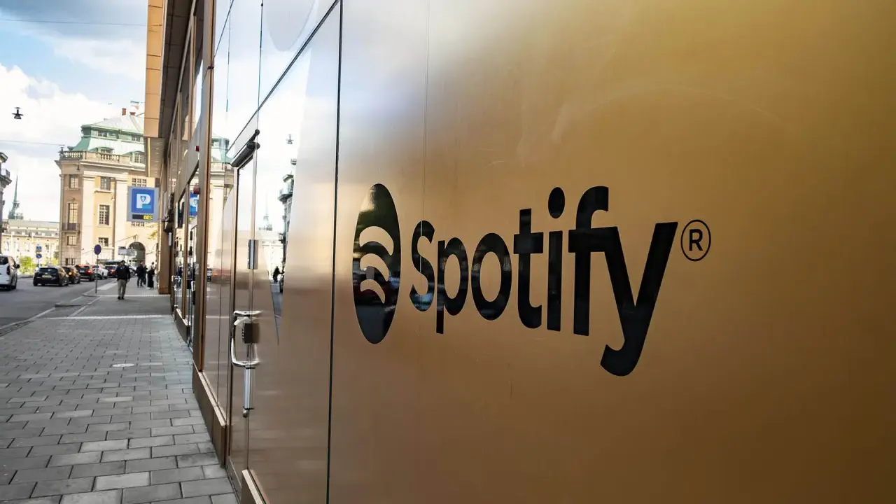 Spotify-logotypen på en guldfärgad fasad. En gata med bilar och människor syns i bakgrunden, vilket antyder att går Spotify med vinst.