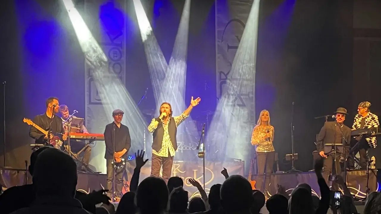 Medlemmar av Dr Hook uppträder på scenen under en konsert, med sångaren i centrum som sjunger i mikrofonen.