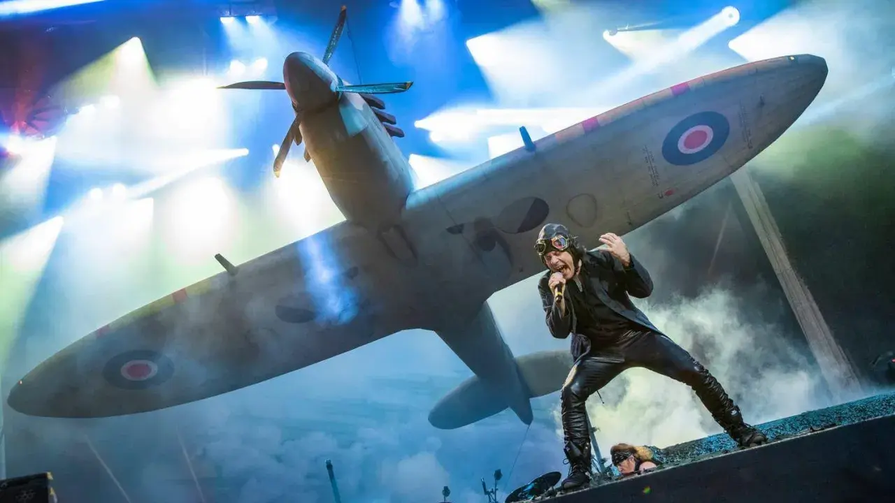 Bruce Dickinson sjunger framför ett Spitfire-plan under Iron Maiden Ullevi. Scenen är fylld av rök och ljus.