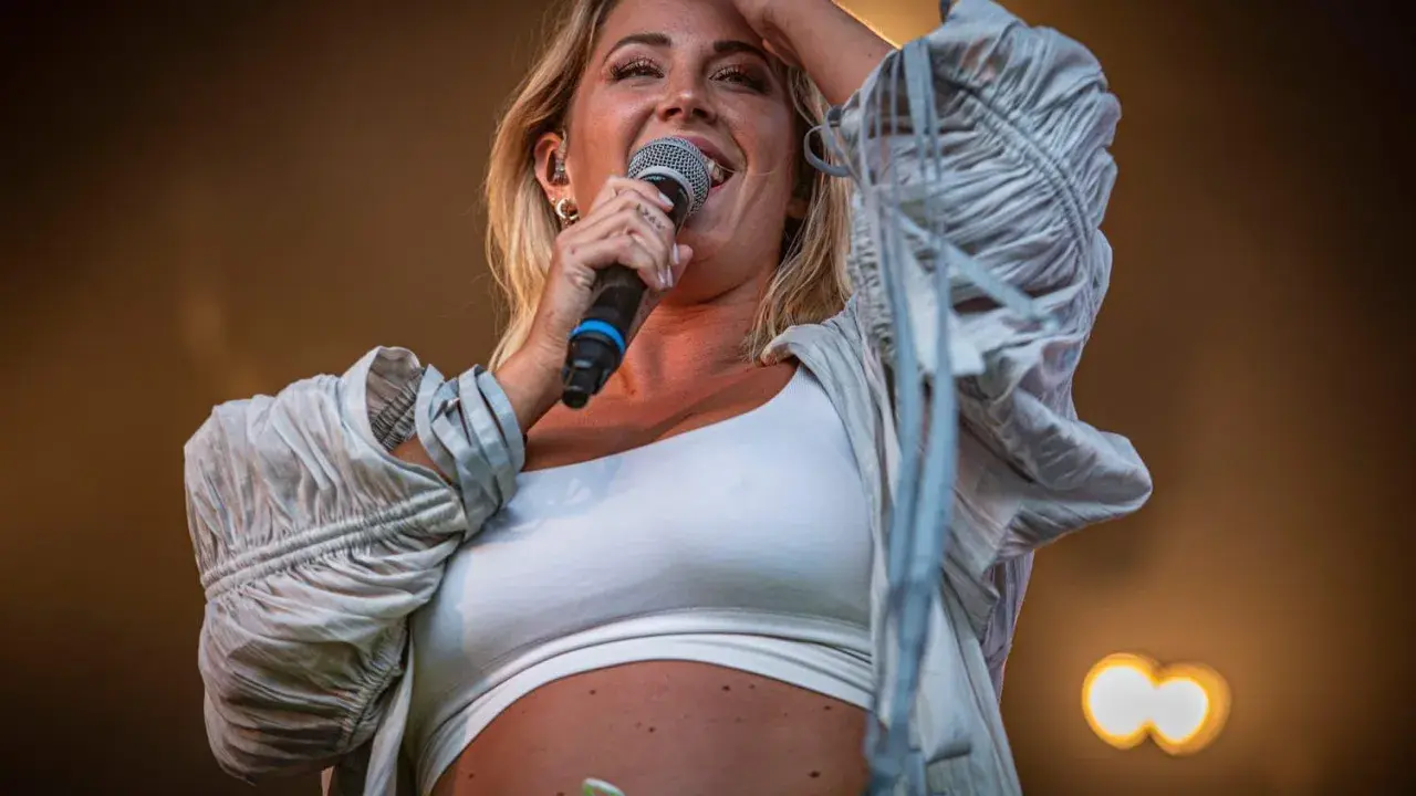 Molly Sandén sjunger på Liseberg, med en mikrofon i handen och ett leende på läpparna.