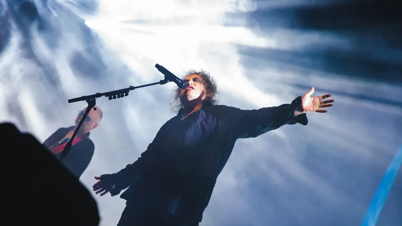 Robert Smith sjunger med utsträckta armar under The Cure i Stockholm.