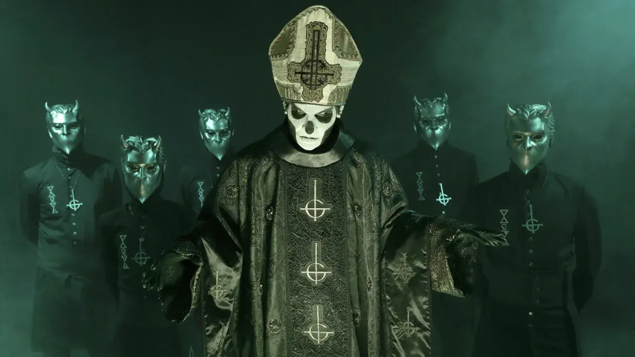 Papa Emeritus IV, klädd i en detaljerad mörkgrön prästrock med korsmotiv, står framför en grupp maskerade följeslagare med horn.