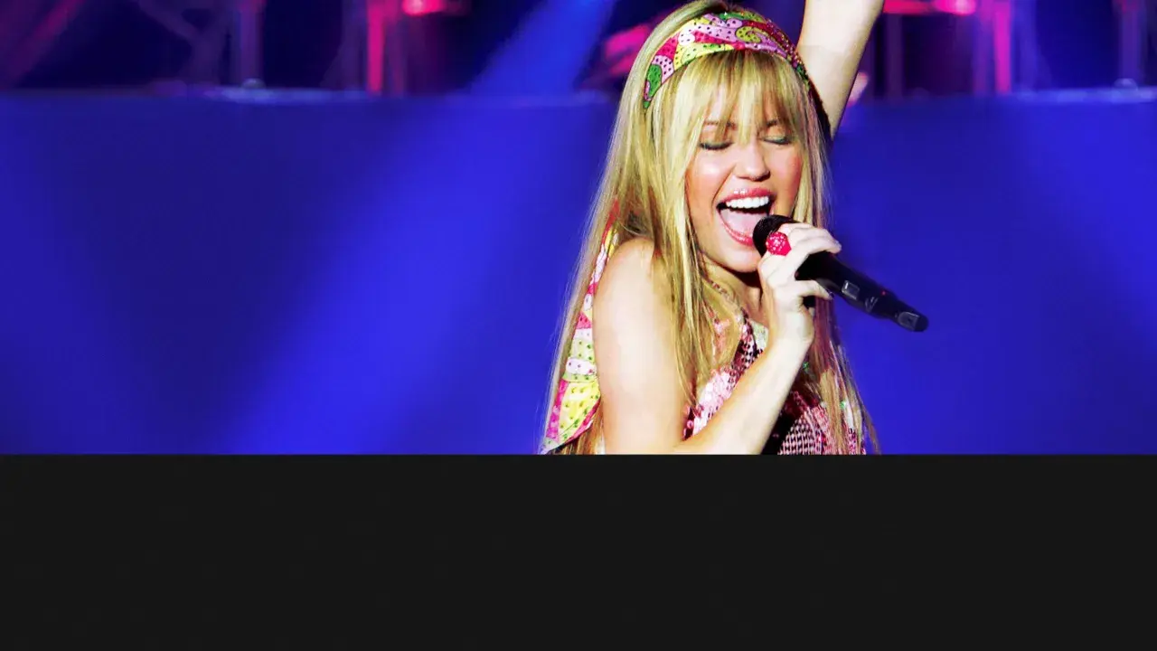 Miley Cyrus sjunger med ett stort leende på scenen i Sverige, iklädd en färgglad topp och pannband.