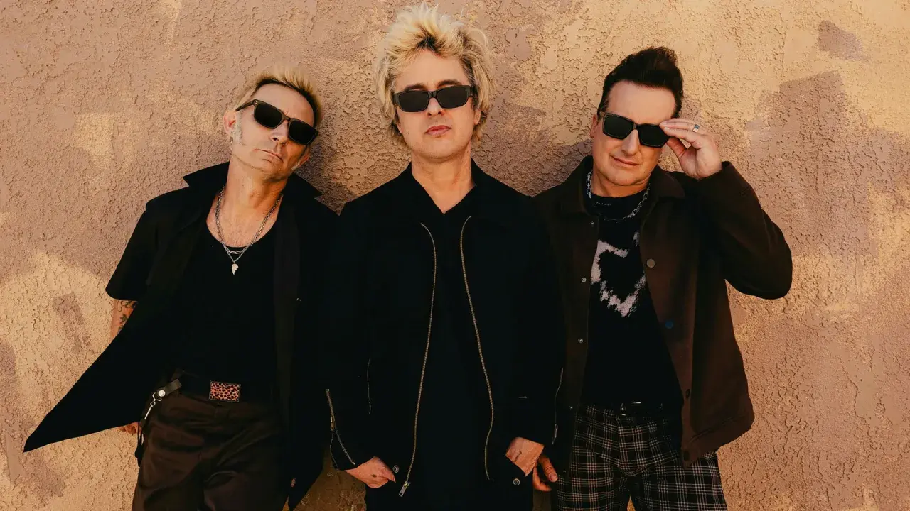 Green Day Sverige: Billie Joe Armstrong, Mike Dirnt och Tré Cool poserar framför en vägg.