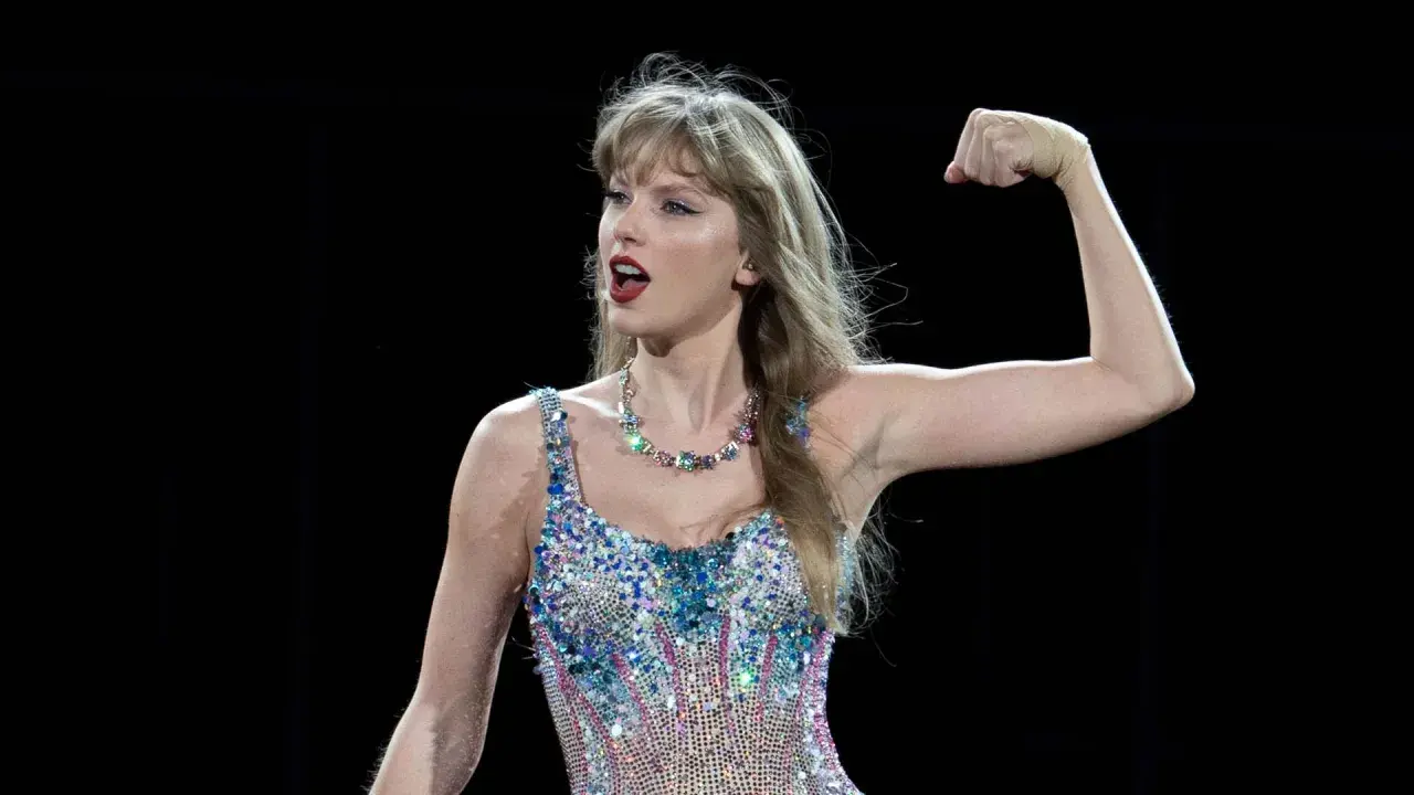 Taylor Swift flexar armen i en glittrig outfit. Undrar du hur mycket kostar Taylor Swift biljetter?