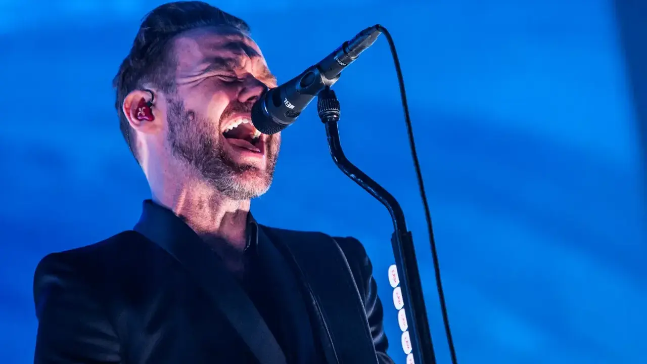 Jocke Berg från Kent sjunger passionerat in i mikrofonen, klädd i en svart kavaj.