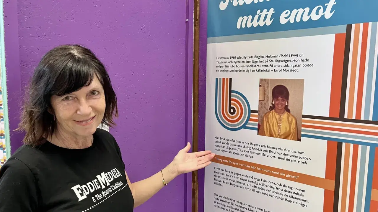 Kvinna i Eddie Meduza-tröja pekar på en utställning om "Flicka i huset mitt emot", en låt av Errol Norstedt.