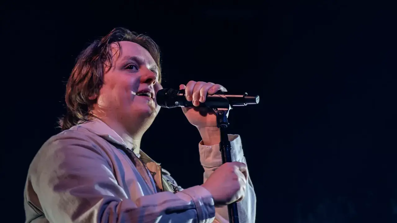 Lewis Capaldi sjunger passionerat på scen i Sverige, med mikrofonen i handen och blicken uppåt.
