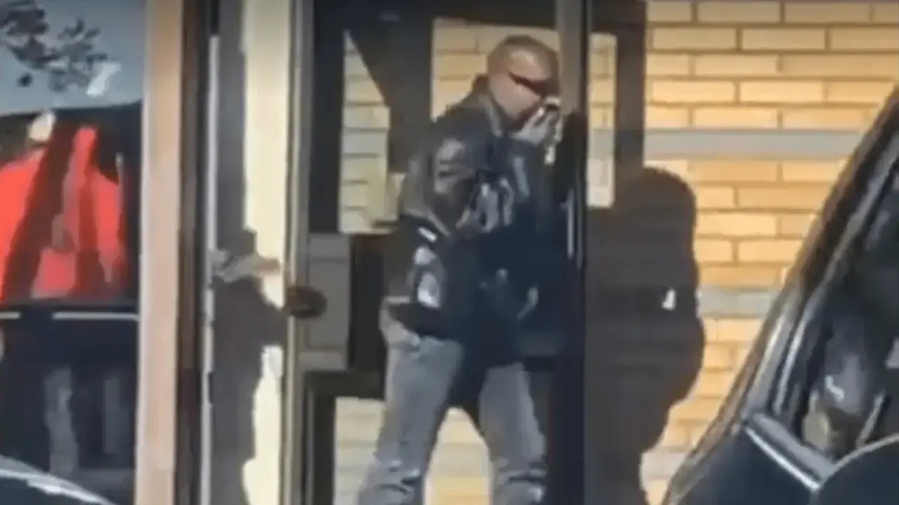 Kanye West i Sverige, klädd i läderjacka och solglasögon, lämnar en byggnad.