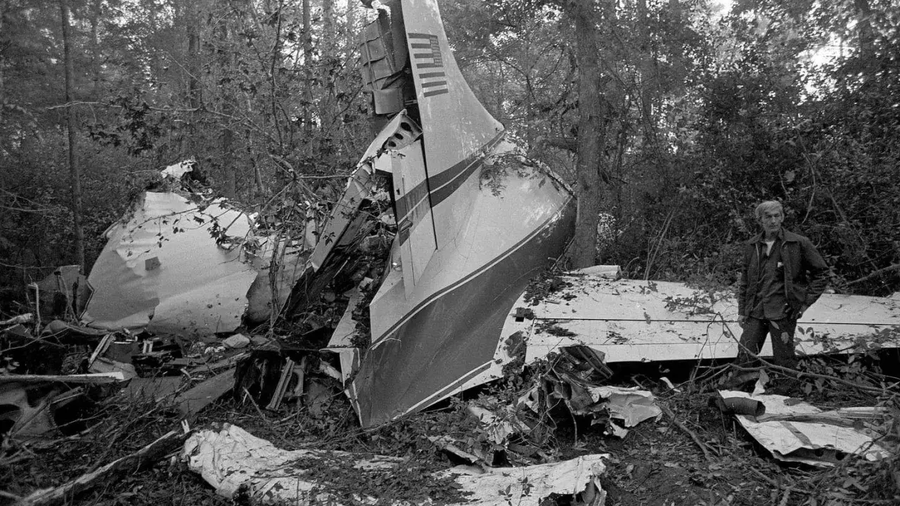 Vraket av ett flygplan i skogen, en man står bredvid. En tragisk påminnelse om lynyrd skynyrd flygolycka.