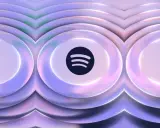 Spotify-logotypen i mitten av en abstrakt, vågig bakgrund i lila och rosa toner. Tänk dig ljudvågor som ger en känsla av spotify hifi.