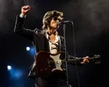 Alex Turner från Arctic Monkeys, med knuten näve i luften, spelar gitarr på scen i Stockholm.