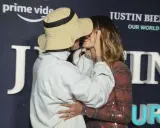 Justin Biebers fru, Hailey, ler när de kysser varandra framför en bakgrund med texten "Justin Bieber: Our World".
