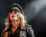 Nicke Andersson från Hellacopters, med sin karaktäristiska keps och läderjacka, fångad i ett intensivt ögonblick på scenen.