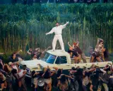 Super Bowl-artister dansar runt en pickup bland majsstjälkar. En artist står på taket.