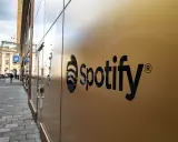 Spotify-logotypen på en guldfärgad fasad. En gata med bilar och människor syns i bakgrunden, vilket antyder att går Spotify med vinst.