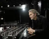 Tomas Ledin lutar sig mot en pianokant i en tom teatersalong, kanske förbereder han sig för Melodifestivalen.