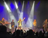 Medlemmar av Dr Hook uppträder på scenen under en konsert, med sångaren i centrum som sjunger i mikrofonen.