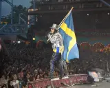 Alice Cooper i Sverige, med svensk flagga och en stor publik som filmar.