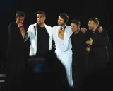 Take that medlemmar! Fem män på scen, en sjunger i mikrofon, andra skrattar och kramas.