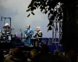 Alice Eva Larsen och hennes band uppträder på scenen. En trummis, en gitarrist i blå kostym och en sittande gitarrist med keps.