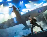 Bruce Dickinson sjunger framför ett Spitfire-plan under Iron Maiden Ullevi. Scenen är fylld av rök och ljus.