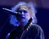 Robert Smith, en av medlemmar av The Cure, sjunger vid en mikrofon med sitt karaktäristiska hår.