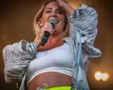 Molly Sandén sjunger på Liseberg, med en mikrofon i handen och ett leende på läpparna.