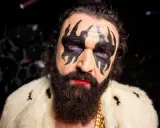 Hank von Hell med dramatisk smink, skägg och en pälskrage.