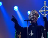 Jocke Berg som Papa Emeritus IV från Ghost, med vit ansiktsmålning och en korsstav, pekar mot publiken under en konsert.