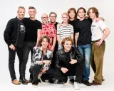 En grupp män, några äldre och några yngre, poserar tillsammans. De ser ut som medlemmar av Gyllene Tider, redo för ett nytt äventyr.