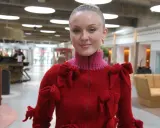 Zara Larsson i USA, klädd i en röd tröja med rosetter, ler mot kameran.