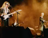 Medlemmar av Eurythmics på scen. Dave Stewart spelar gitarr, Annie Lennox sjunger. En saxofonist och en keyboardist syns också.