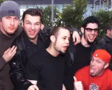 Medlemmar av Limp Bizkit poserar glatt för en bild. En person i röd keps sticker ut tungan.