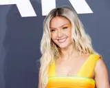 Zara Larsson ler glatt i en färgglad klänning, hennes framgångar som artist bidrar till hennes imponerande zara larsson net worth.