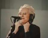 Eva Dahlgren med hörlurar och mikrofon, fångad i ett känslosamt ögonblick under en konsert.