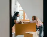 Par diskuterar flytten utomlands, omgivna av flyttkartonger. En checklista för flytten är troligen nära till hands.
