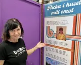 Kvinna i Eddie Meduza-tröja pekar på en utställning om "Flicka i huset mitt emot", en låt av Errol Norstedt.