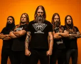 Amon Amarth tour: fem vikingar med långt hår och skägg poserar framför orange bakgrund.