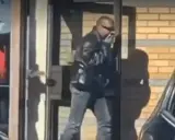 Kanye West i Sverige, klädd i läderjacka och solglasögon, lämnar en byggnad.