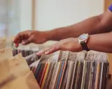 Händer bläddrar bland skivomslag, letar efter det mest sålda albumet.