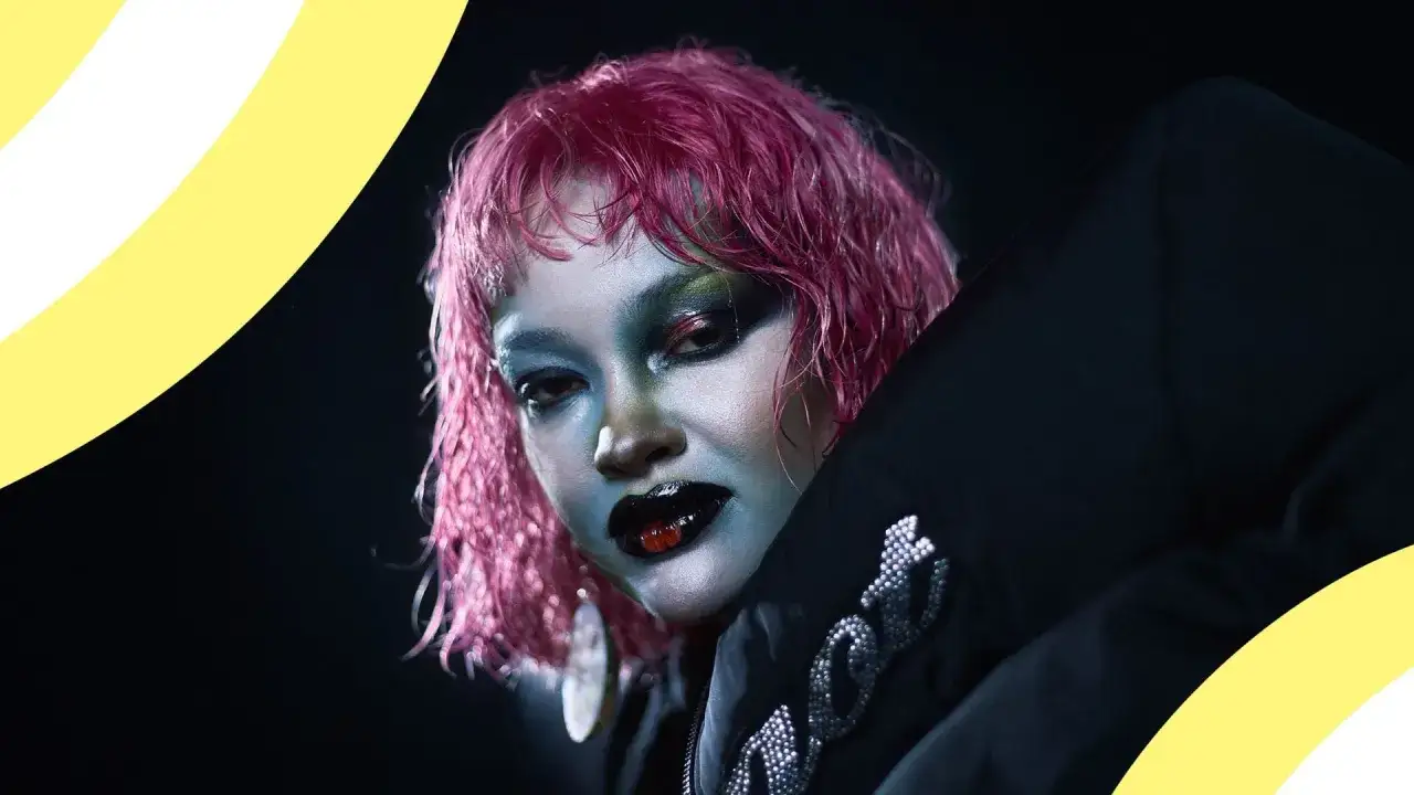 Daniela Rathana med rosa hår och dramatisk makeup, klädd i en svart jacka med strassdetaljer.