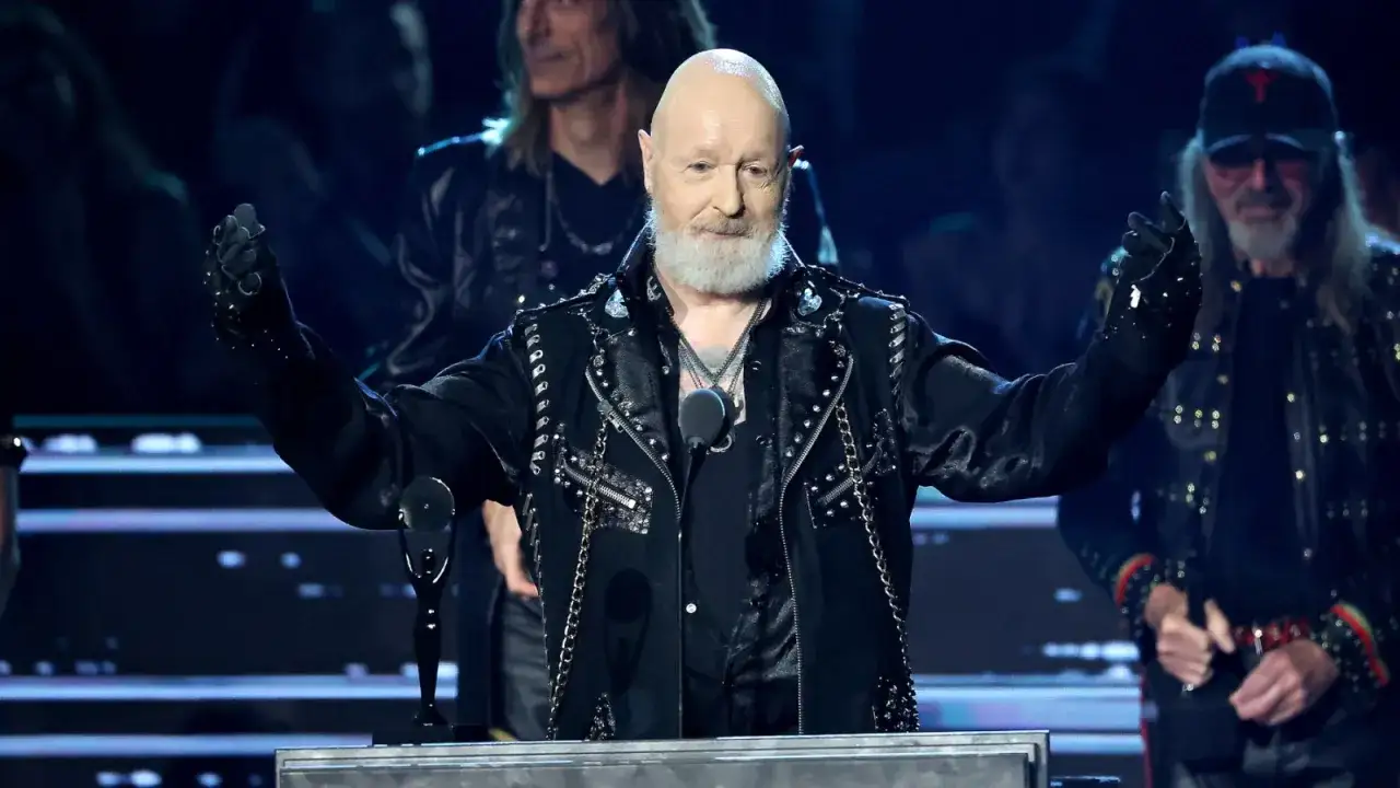 Rob Halford, en av medlemmar av Judas Priest, med armarna utsträckta, iklädd en svart läderjacka med nitar och kedjor.