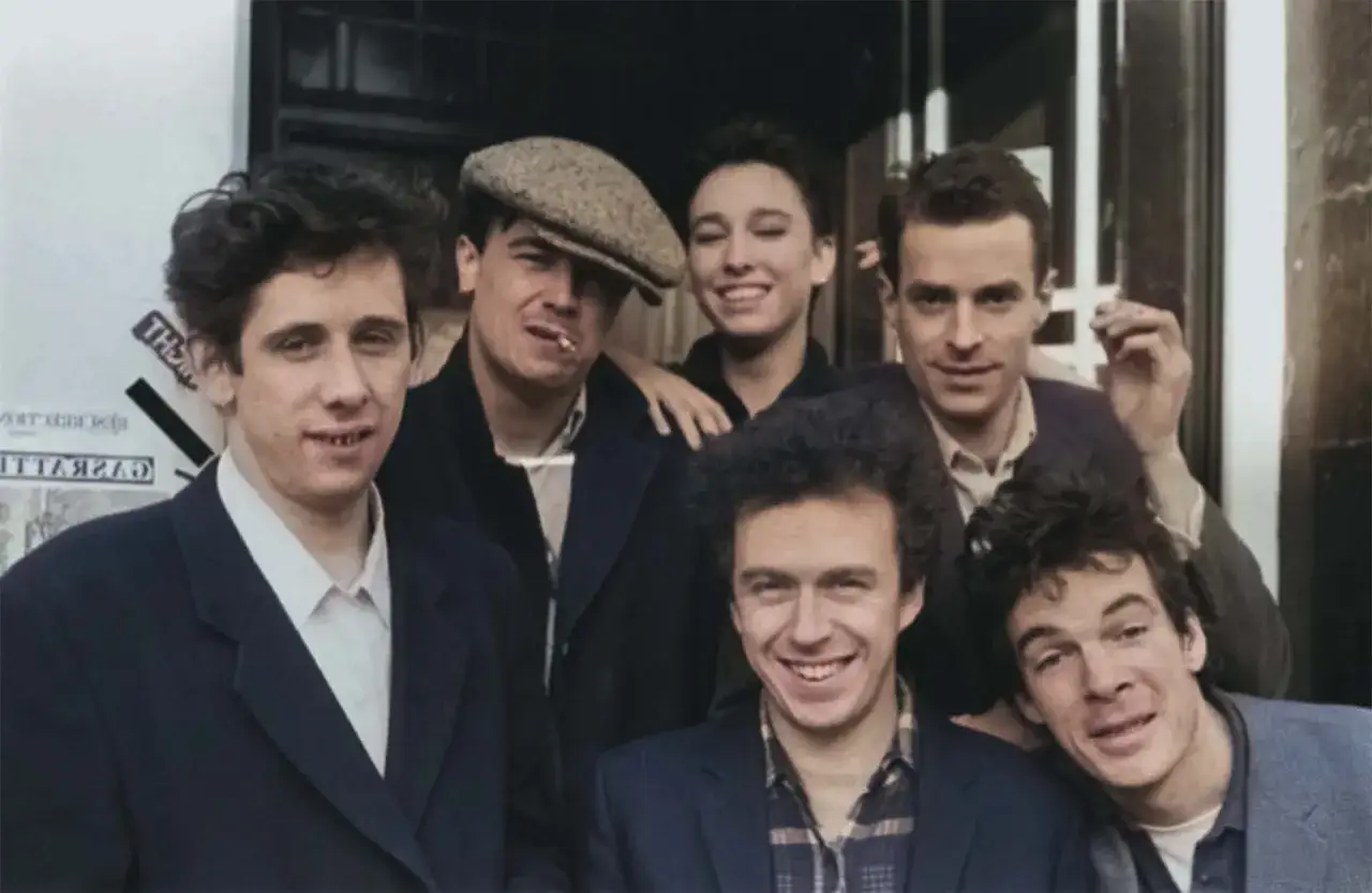 Medlemmar av the Pogues samlade, med en kepsbeklädd man som röker.