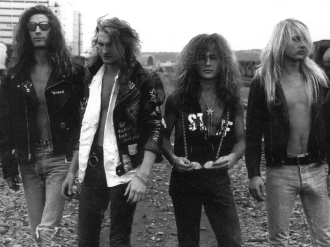 Medlemmar av Alice in Chains poserar utomhus. De har långt hår och kläder i rockstil.