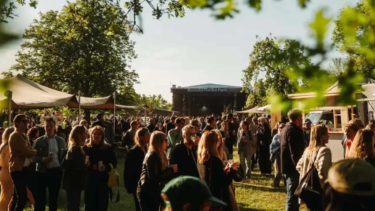 Folk samlas vid en scen under Rosendal Garden Party. Solen skiner och stämningen är festlig.